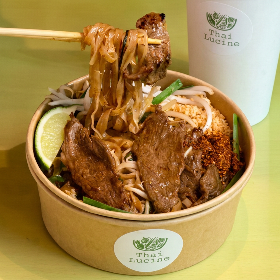 Thai Lucine bowl of noodles topped with grilled beef, bean sprouts, lime, herbs, and chili, lifted with chopsticks.